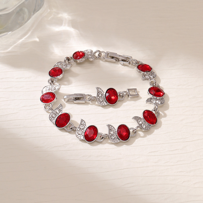 Silver-tone bracelet with red oval stones, clear leaf accents and a clasp.