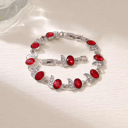 Silver-tone bracelet with red oval stones, clear leaf accents and a clasp.