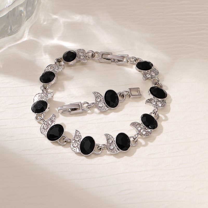 Silver-tone bracelet with black oval stones, clear leaf accents and a clasp.