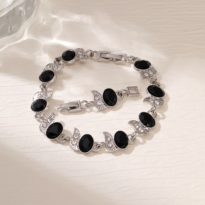 Silver-tone bracelet with black oval stones, clear leaf accents and a clasp.