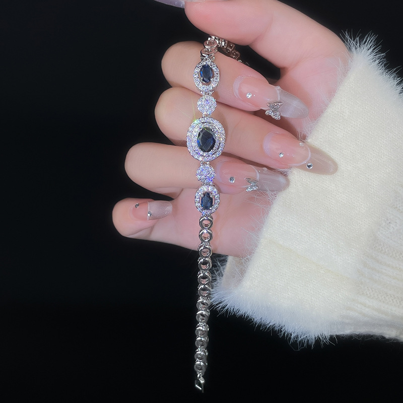 Silver-tone bracelet with dark oval center stones, clear halos and small round links.