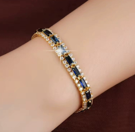 Gold-tone three-row bracelet with blue rectangular center stones bordered by small clear accents.