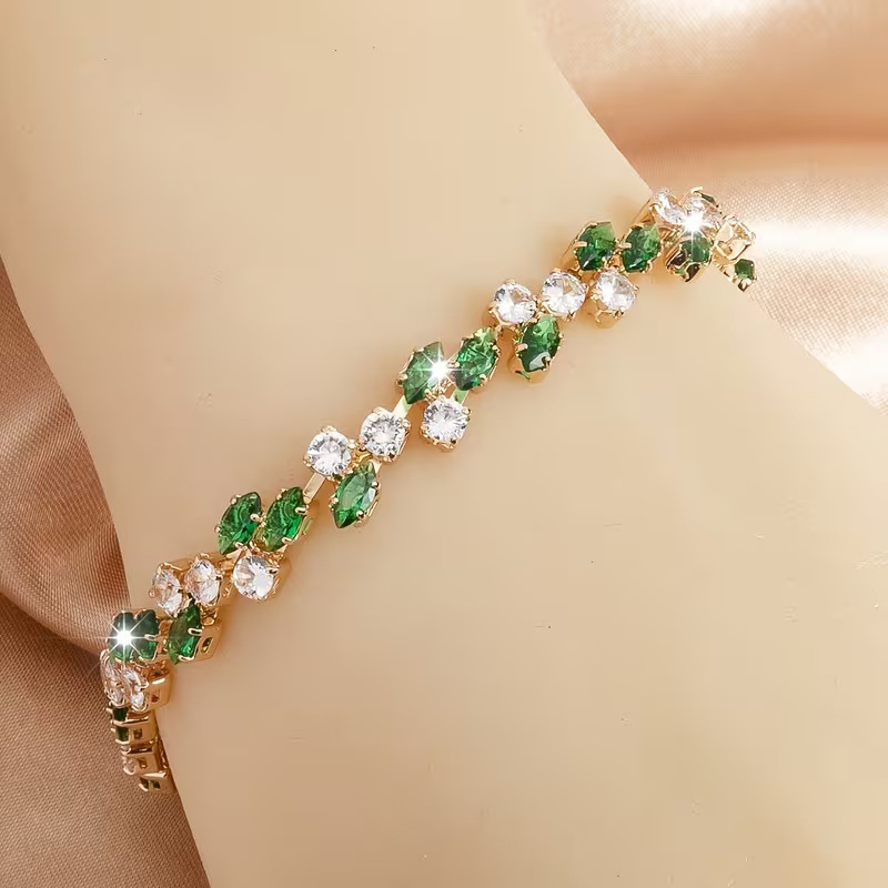 Gold-tone bracelet with green marquise-shaped stones and round clear accents in a leaf-like pattern.