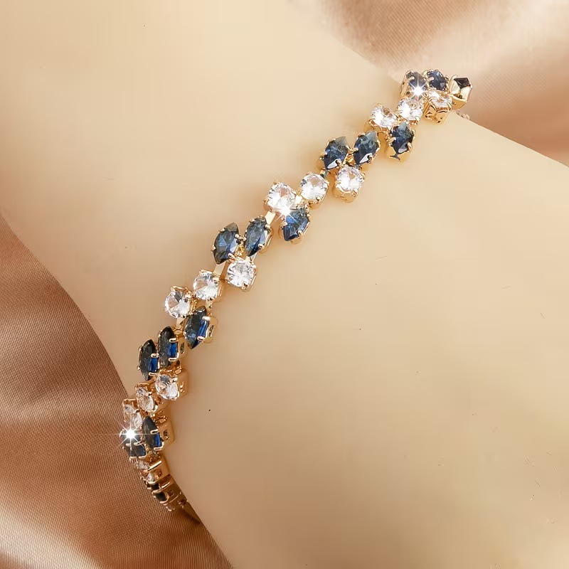 Gold-tone bracelet with blue marquise-shaped stones and round clear accents in a leaf-like pattern.