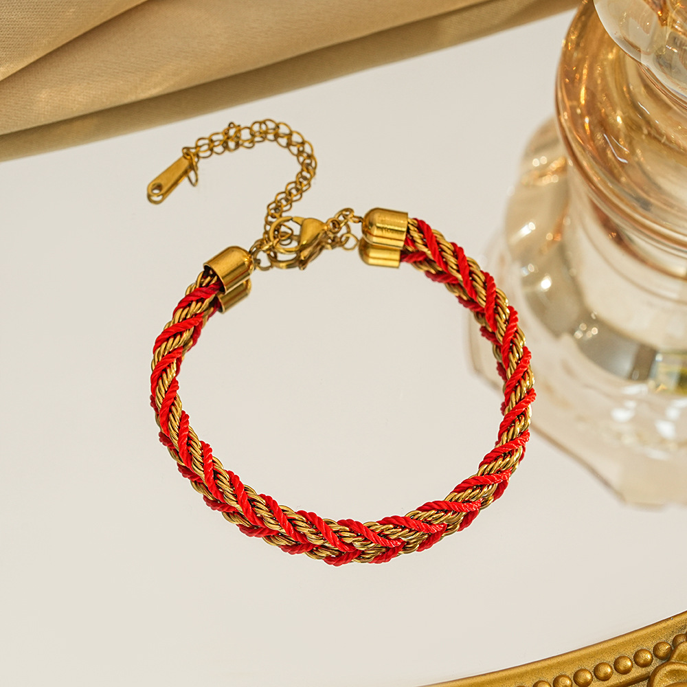 Braided bracelet in red / gold tone with gold-tone end caps, a lobster clasp and extension chain.