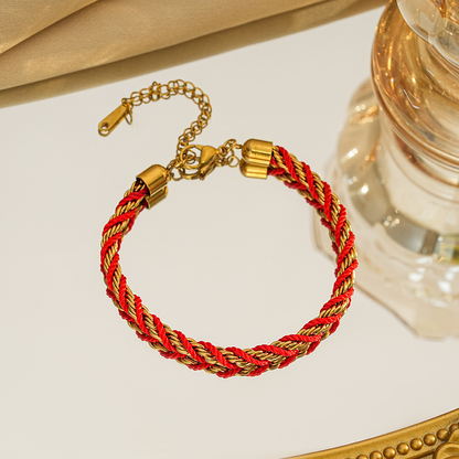 Braided bracelet in red / gold tone with gold-tone end caps, a lobster clasp and extension chain.
