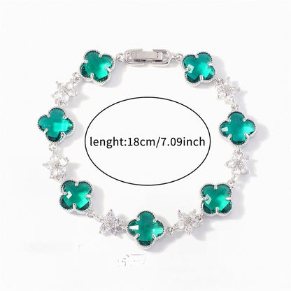 Silver Tone bracelet with green four-leaf clovers and small clear flower links; length 18 cm.