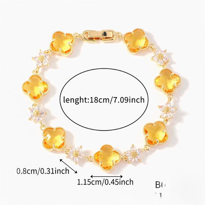 Gold Tone bracelet with yellow four-leaf clovers and small clear flower links; length 18 cm.