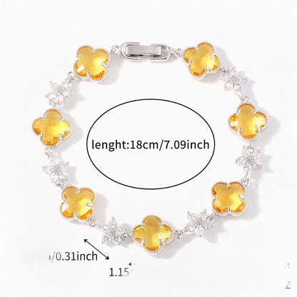 Silver Tone bracelet with yellow four-leaf clovers and small clear flower links; length 18 cm.