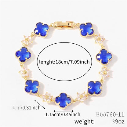 Gold Tone bracelet with blue four-leaf clovers and small clear flower links; length 18 cm.