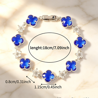 Silver Tone bracelet with blue four-leaf clovers and small clear flower links; length 18 cm.