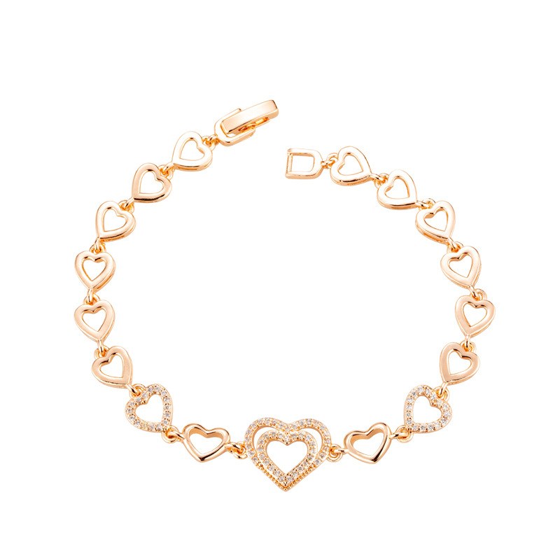 Gold-tone open-heart link bracelet with a larger stone-set heart center and two smaller heart accents.