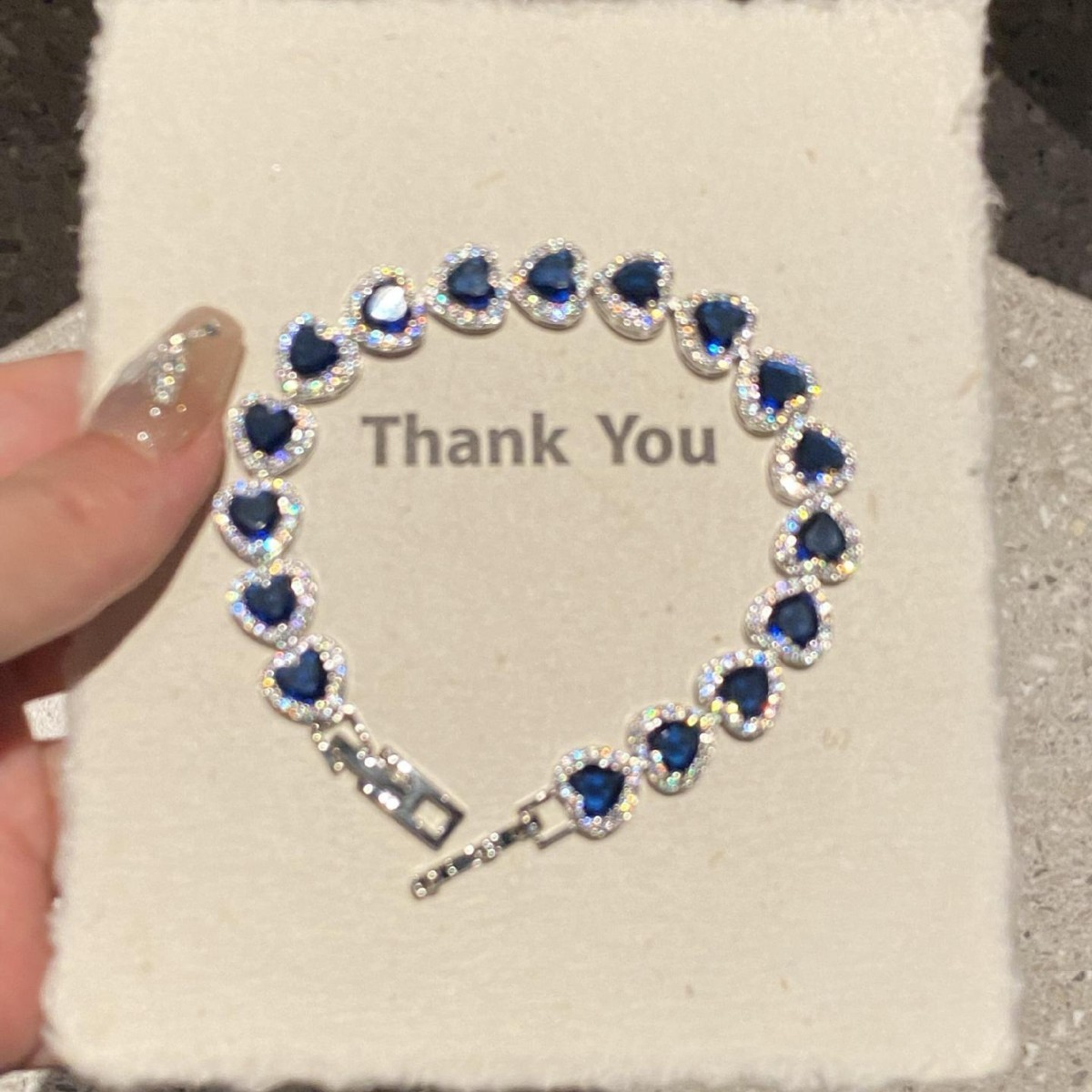 Silver-tone bracelet with repeating dark blue heart-shaped stones bordered by clear accents.