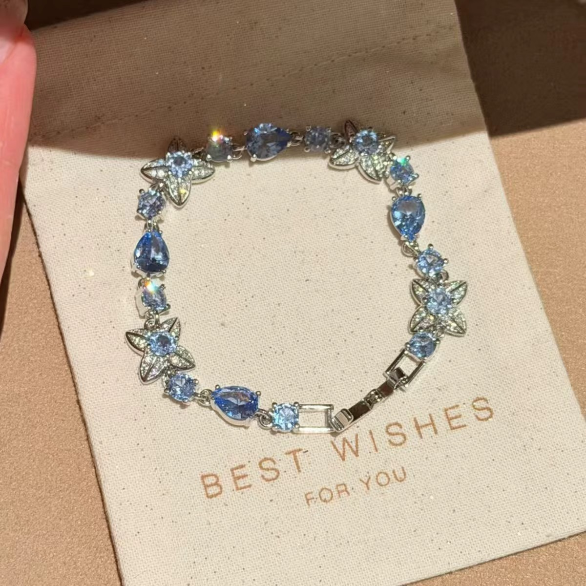 Silver-tone bracelet with blue teardrop accents and open butterfly-like motifs.