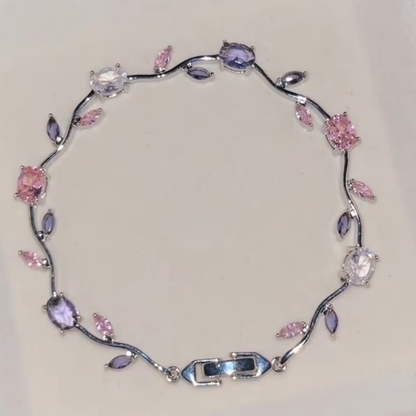Silver-tone bracelet with curved vine links, small leaves and pink and purple flower accents.