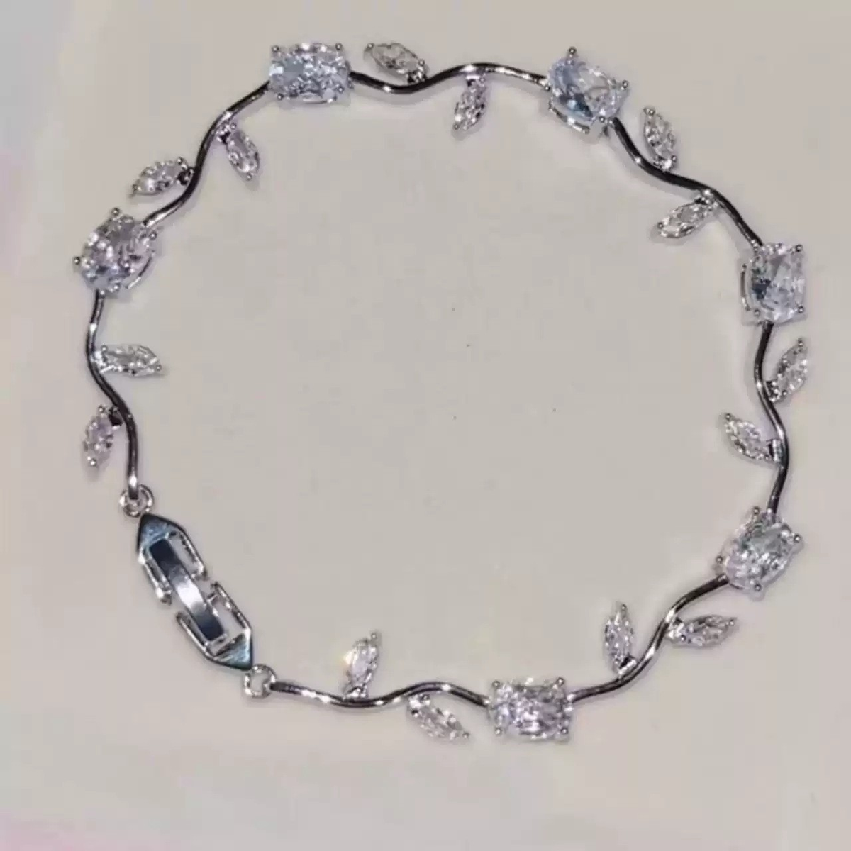 Silver-tone bracelet with curved vine links, leaf accents and clear flower-shaped center stones.