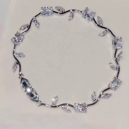 Silver-tone bracelet with curved vine links, leaf accents and clear flower-shaped center stones.