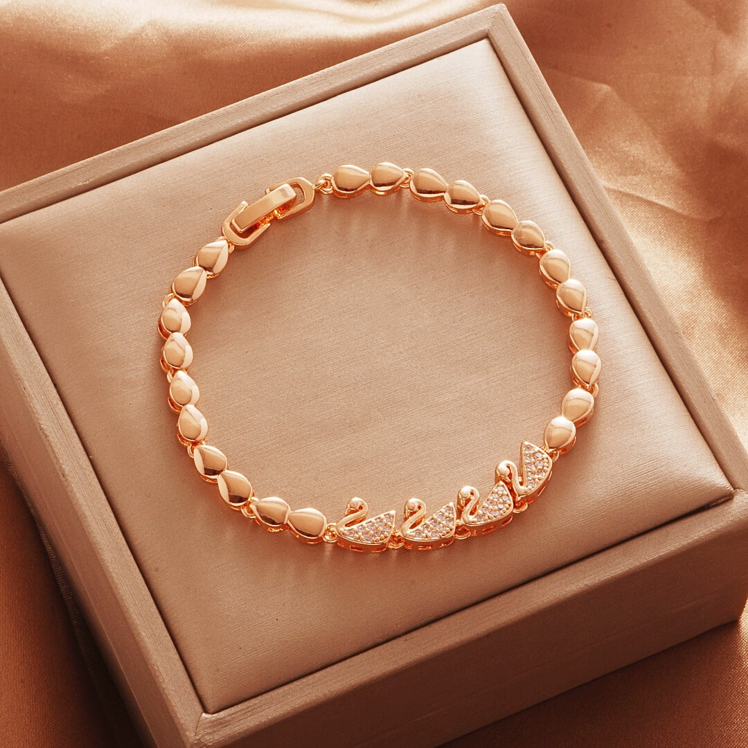 Gold Tone bracelet, style TSL002, with curved stone-set center motifs and smooth oval links and a clasp.