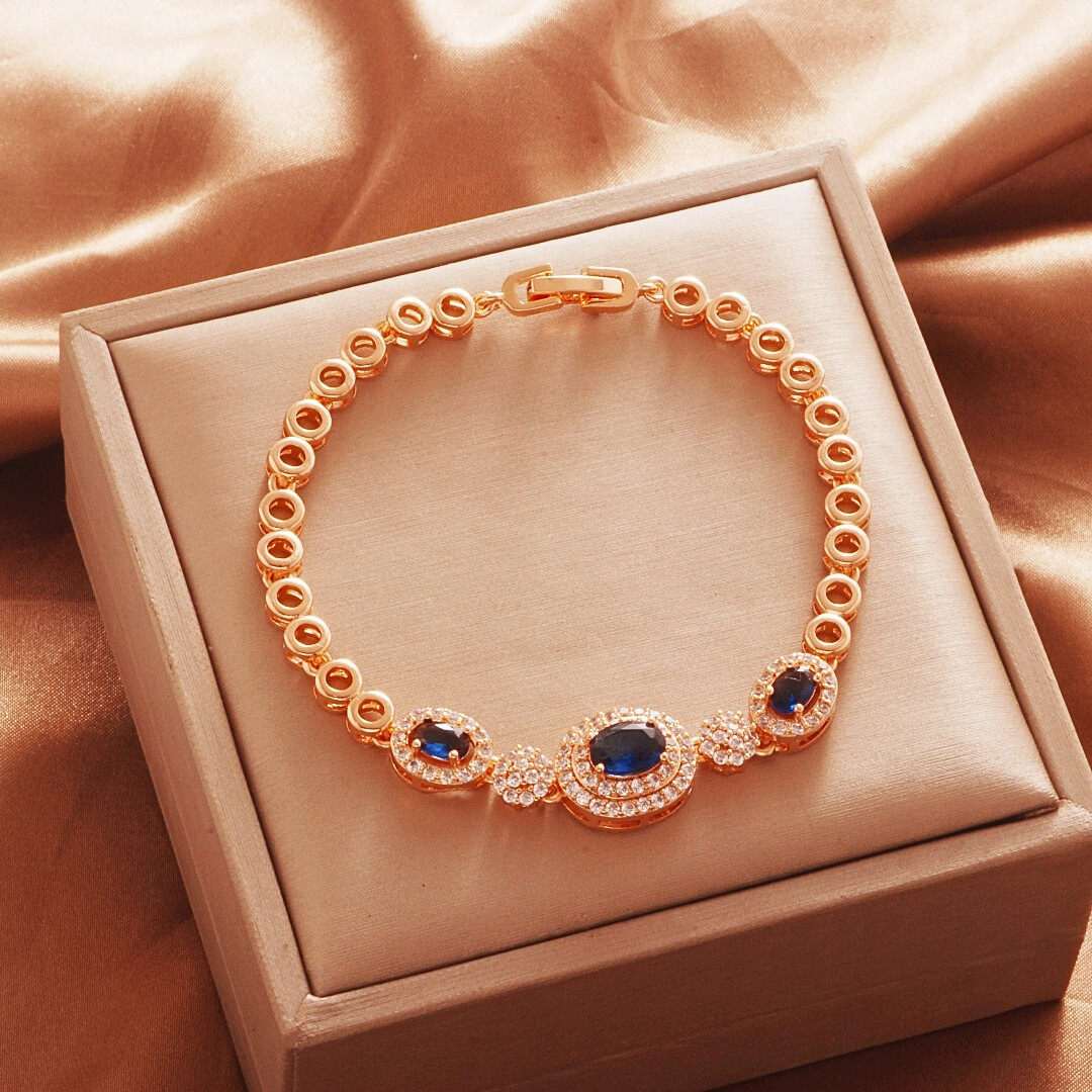 Gold Tone bracelet, style TSL003, with dark blue oval halo centers and round links and a clasp.