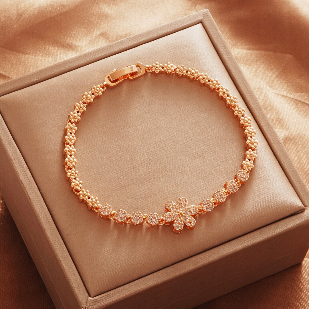 Gold Tone bracelet, style TSL010, with a stone-set flower center and small decorative links and a clasp.