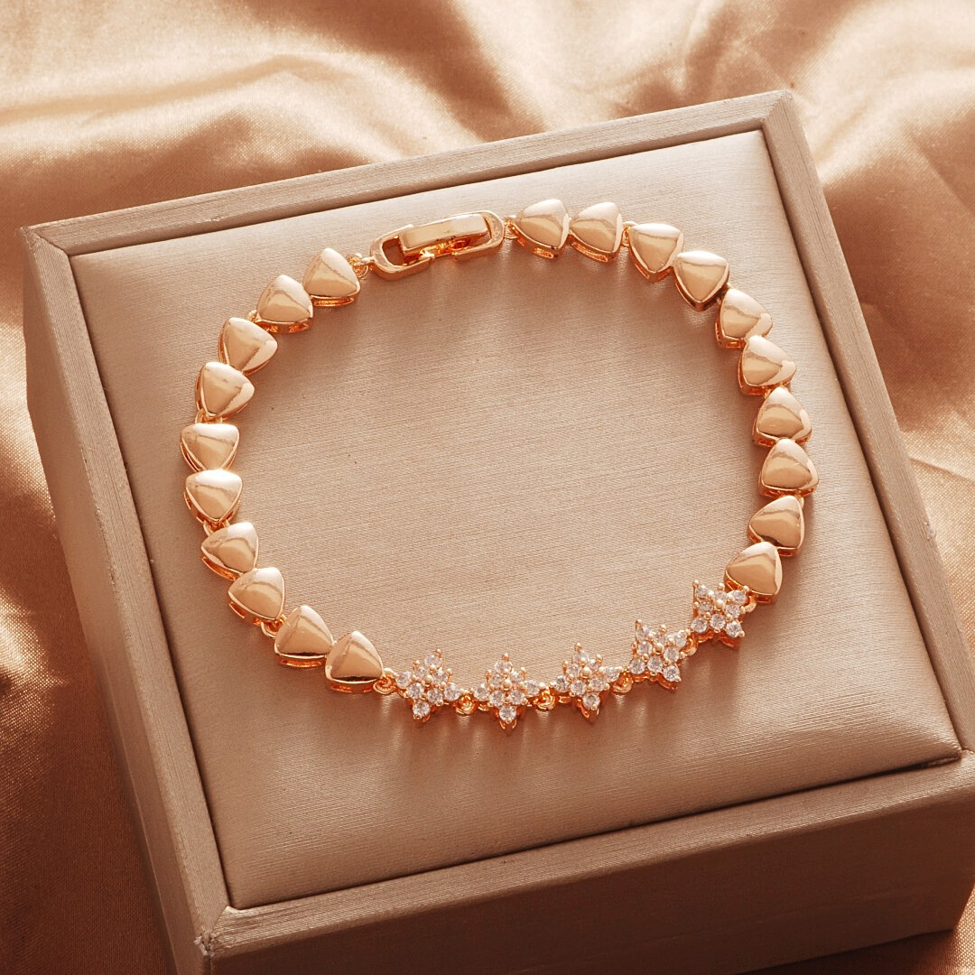 Gold Tone bracelet, style TSL016, with a floral stone-set center and polished heart-shaped links and a clasp.